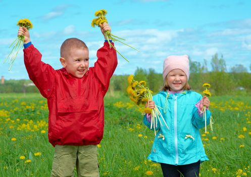 boy and small girl  on meadow with dandelion