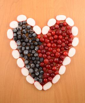 Frozen cranberries and  blackberry are laid out in the form of heart close-up