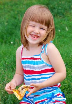 Picnic on the grass. small girl  have a dinner with pizza on the meadow .