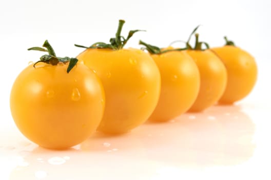 Juicy ripe yellow tomatos  in drops of water on a white background