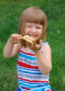 Picnic on the grass. small girl  have a dinner with pizza on the meadow .