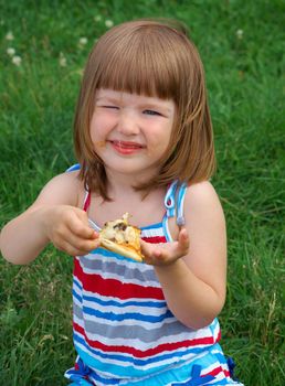 Picnic on the grass. small girl  have a dinner with pizza on the meadow .