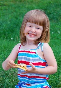 Picnic on the grass. small girl  have a dinner with pizza on the meadow .