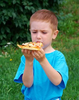 Picnic on the grass. boy   have a dinner with pizza on the meadow .