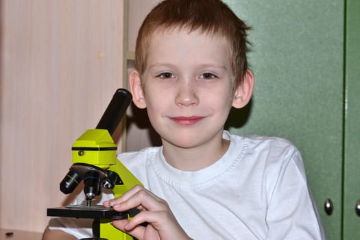 The boy looks in a microscope