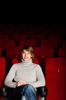 young man in casual sitting in the cinema and watching a movie