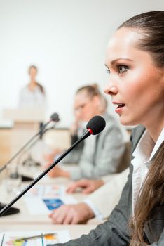 businessmen talking at the conference, sitting at the table, on the table microphones and documemts