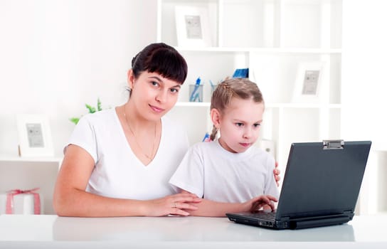 Mom and daughter are working together for a laptop at home