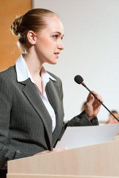 Portrait of a business woman holding a microphone and looks ahead