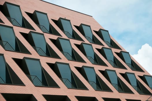 Pink modernd building with many black windows and blue sky
