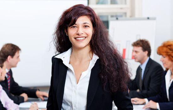 professional successful smiling business woman in office with team in background