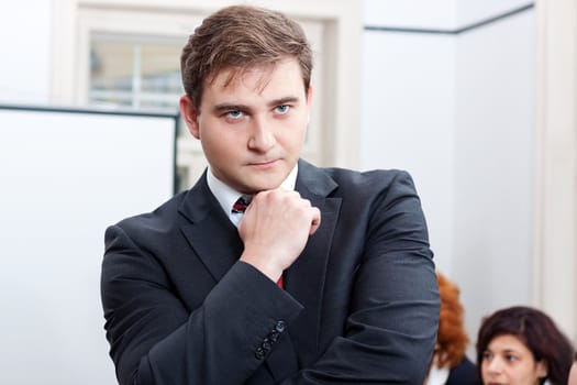 successful business smiling man portrait at office with team in background