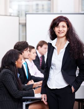 professional successful smiling business woman in office with team in background