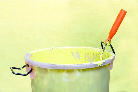 Paint-roller and Paint bucket with paint on a green background