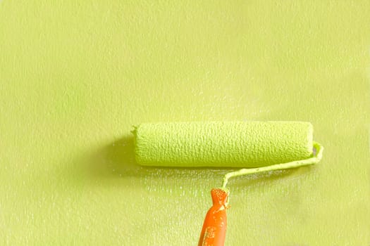 Wall painter using a paint roller, painting a wall in motion