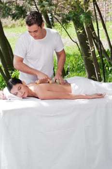 Young man giving massage to woman by a wooden massager