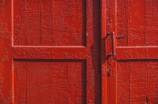 An old wood door with cracked red paint and grunge