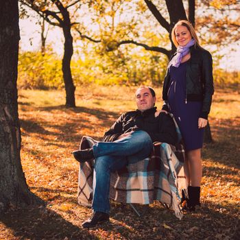 Pregnant woman and her husband in autumn forest