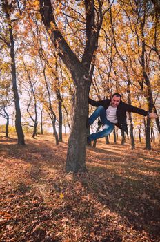 Man climbing tree in yellow autumn forest