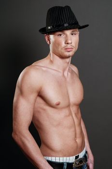 Studio portrait of young bald muscular man with black hat