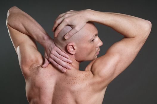 Portrait of naked athletic man posing over gray background