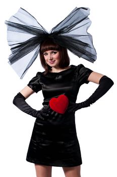 Pretty girl in black dress and big bow with red heart in her hands isolated on white background