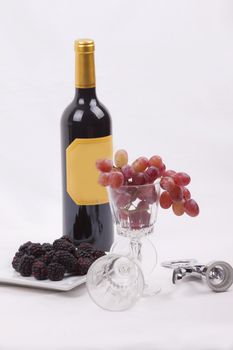 Bottle of red wine, and glass filled with grapes