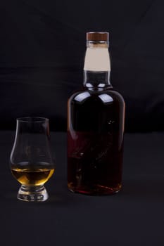 glass and bottel of whisky on a black background