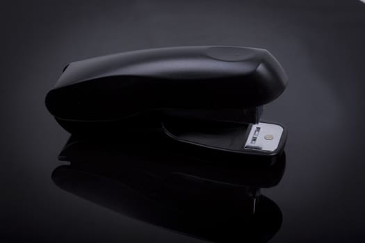 photo  of a stapler on a black shiny background