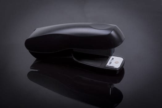 photo  of a stapler on a black shiny background