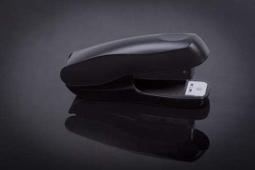 photo  of a stapler on a black shiny background