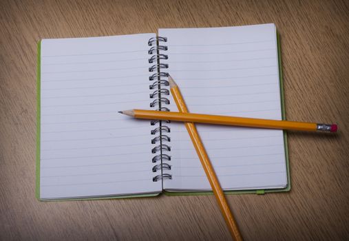 open  notebook on a wooden desk with pencil