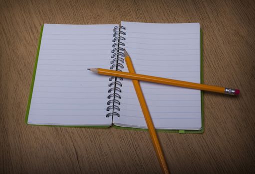 open  notebook on a wooden desk with pencil