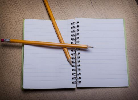 open  notebook on a wooden desk with pencil