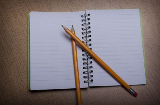 open  notebook on a wooden desk with pencil