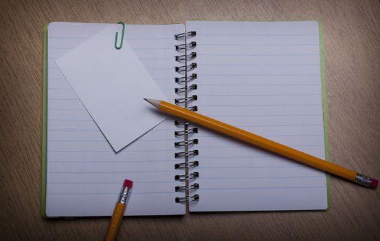 open  notebook on a wooden desk with pencil