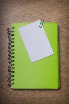 green notebook on a wooden desk