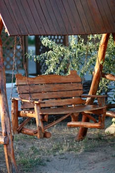 Wooden chain swing in a bench under a canopy in summer day