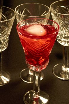 Empty crystal glasses and a glass of red wine with ice