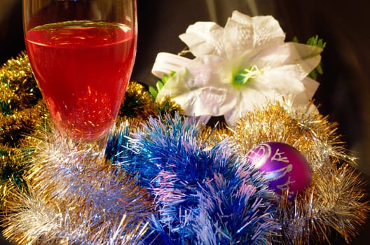 Glass of red wine and white artificial flower decorated  garlands and Christmas ball on a black background