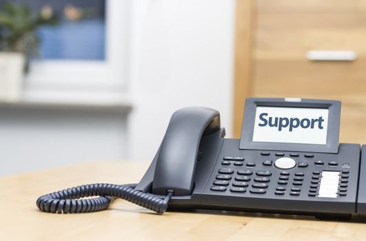 modern voip phone with the word -support- on display. Blurred background