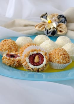 Cheese balls stuffed with cherries in peanuts and coconut flakes