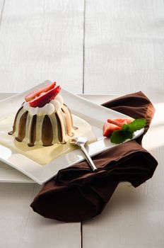 chocolate pudding with vanilla sauce strawberry and mint on white plate