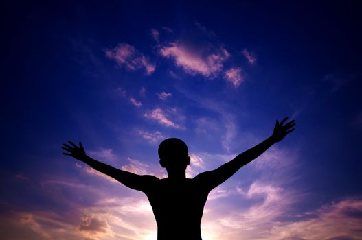 Silhouette or backlit of Asian man open arms raised towards sky on sunset