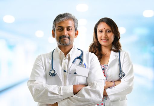Indian doctors or medical tem crossed arms standing, hospital background