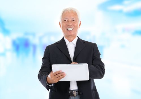 Asian senior businessman using tablet-pc standing office background
