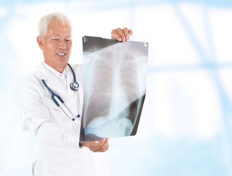 Asian senior doctor checking on x-ray image inside hospital room