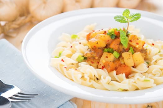 Pasta fusilli with potatoes, carrot and tomatoes on the kitchen table