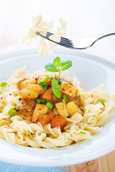 Delicious pasta fusilli with potatoes, carrot and tomatoes on the kitchen table