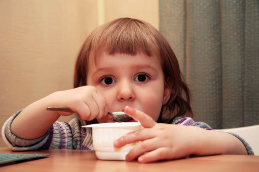 The little girl eats yoghurt of at home